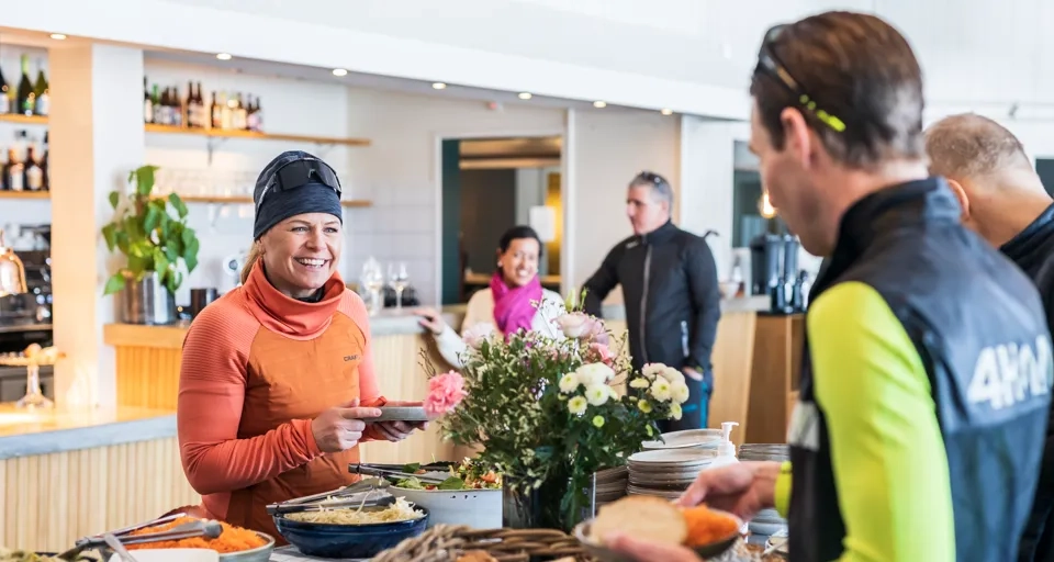 A group of people standing around a table filled with food.