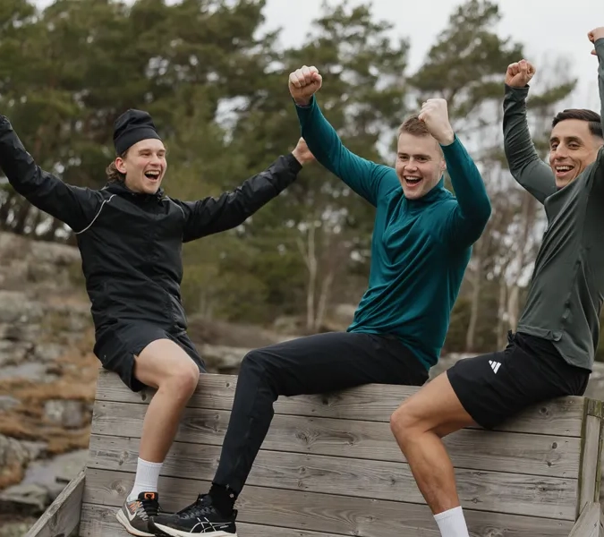 A group of young men sitting on top of a wooden bench.