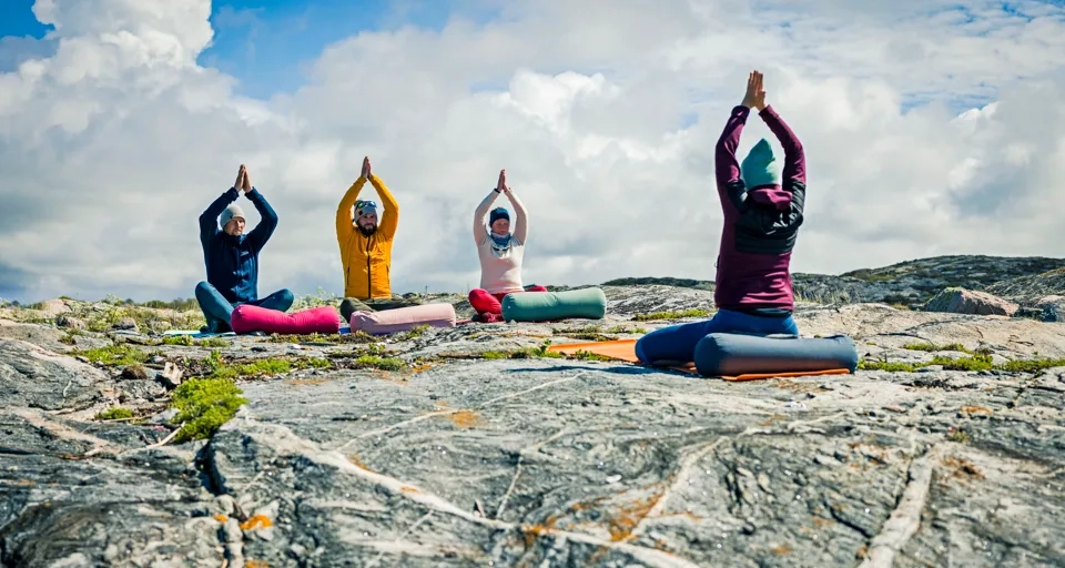 A group of people doing yoga on top of a mountain.
