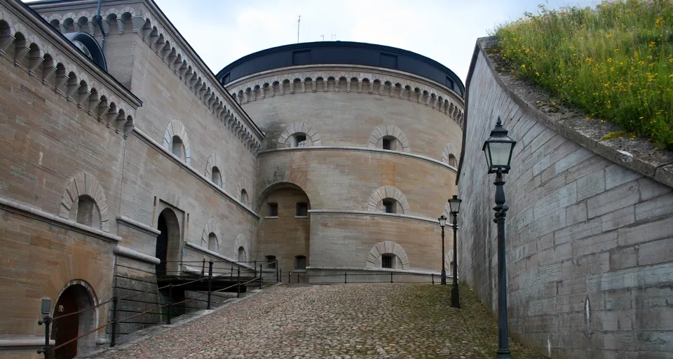 A stone building with a green roof next to a street light.