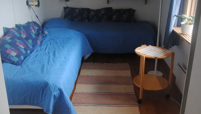 Ett sovrum med två sängar, ett bord och ett fönster.