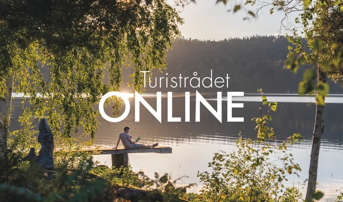 En man sitter på en båt på en sjö.