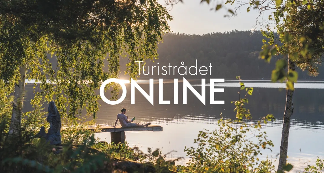 En man sitter på en båt på en sjö.