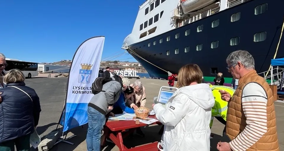 En grupp människor som står runt en röd bänk.