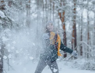 Kvinna som kastar upp snö från marken mot kameran