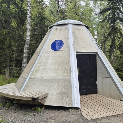 Ett rymdskepp i trä mitt i en skog.