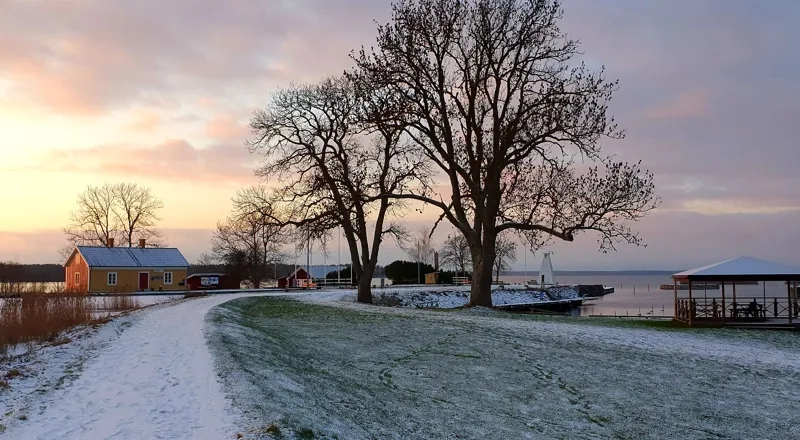 A snow covered path next to a body of water.