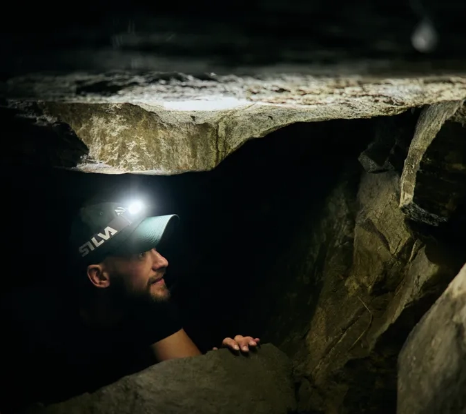 En man i en grotta med en ficklampa på huvudet.