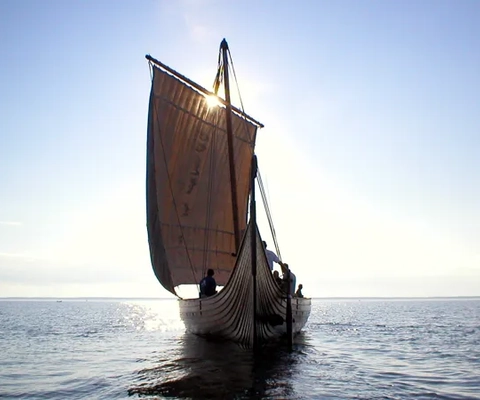 Ett vikingaskepp i kvällssolen på öppet vatten.