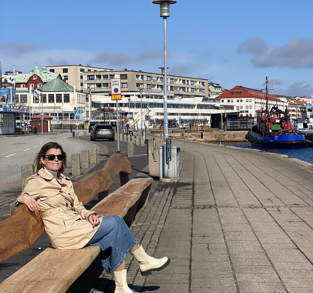 En kvinna sitter på en bänk nära vattnet.