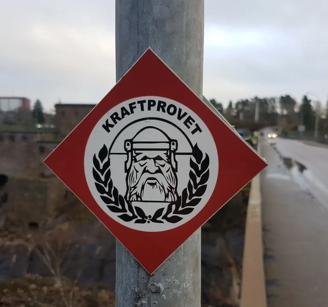 En gatuskylt på en stolpe vid en väg.