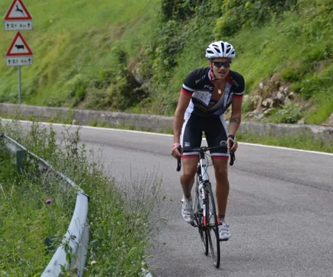 En mann sykler nedover en svingete vei.