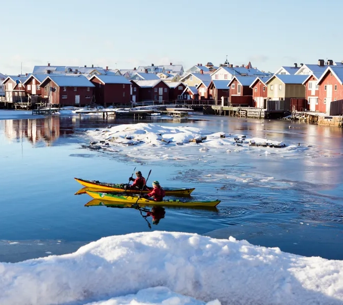 Et par mennesker i en gul kajakk på et vann.