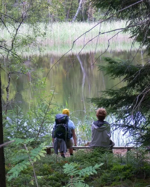 To personer sitter på en benk og ser på en innsjø.