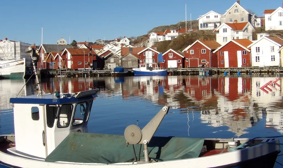 En blå och vit båt som flyter på ett vattendrag.