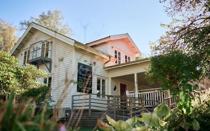 Ett vitt hus med rött tak och en veranda.