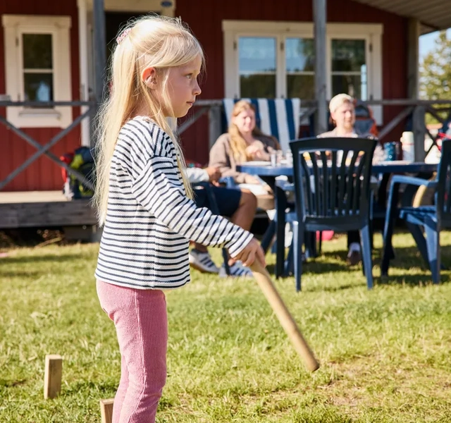 Ett barn spelar utomhusspel på en gräsmatta.