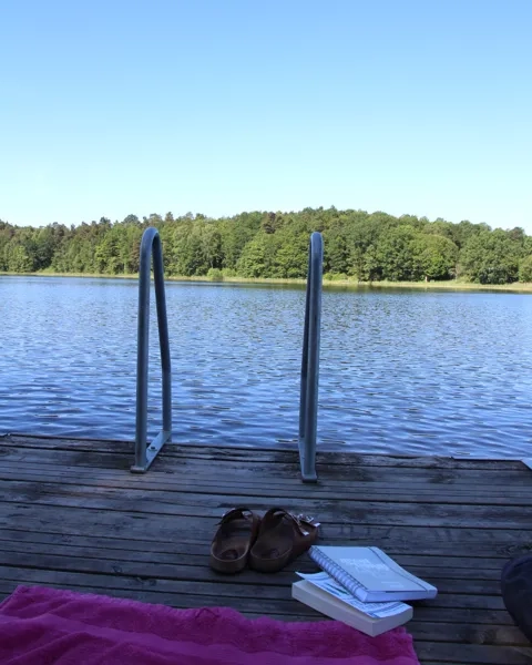 Ett par flip flops som sitter på en brygga intill ett vattendrag.