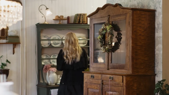 En kvinna står i ett kök bredvid ett träskåp.