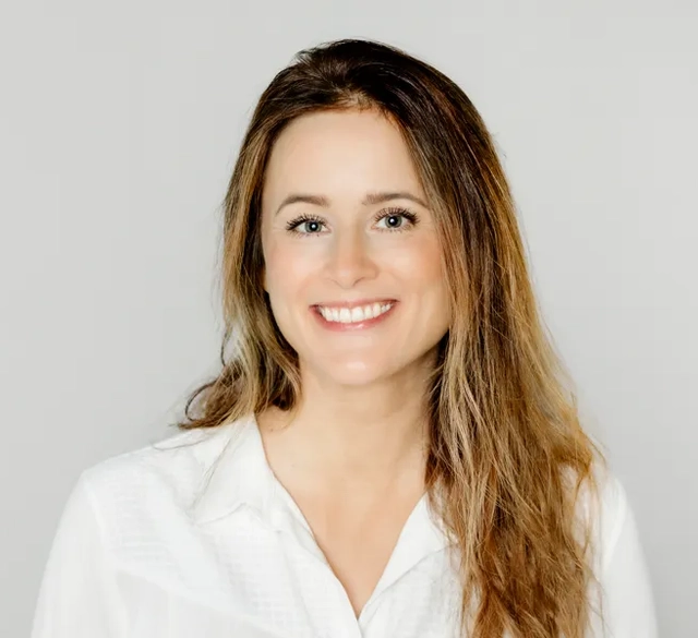 En kvinna med långt hår som bär en vit skjorta.