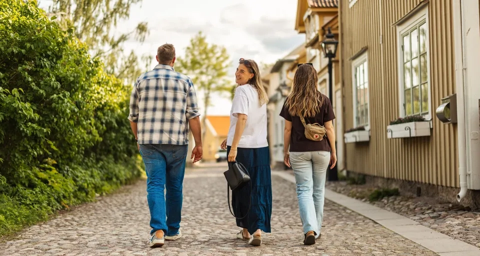 Eine Gruppe von Menschen, die eine Straße mit Kopfsteinpflaster entlanggeht.