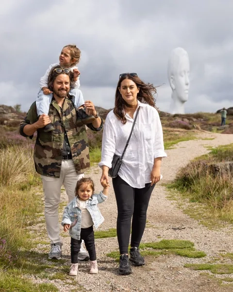 Familj promenerar i en skulpturpark ute i naturen.