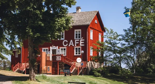 Rött hus bland gröna träd.