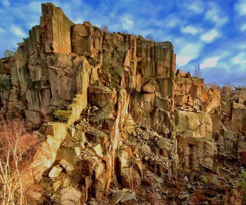 En målning av ett klippigt landskap med träd och stenar.