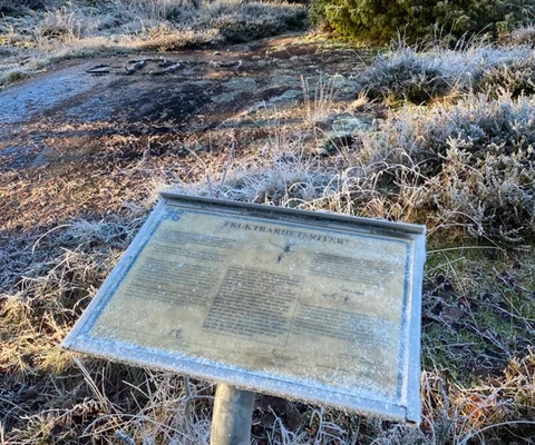 En skylt som sitter mitt på ett grästäckt fält.