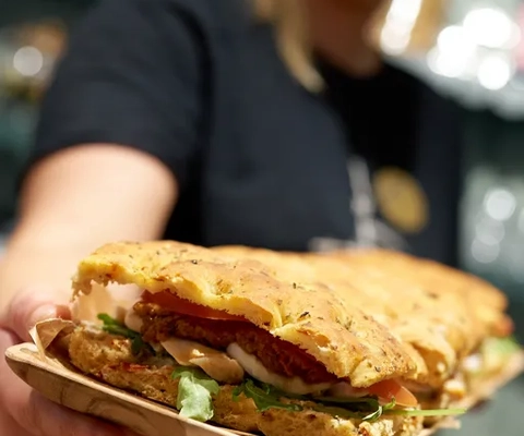 En person som håller i en tallrik med en smörgås.