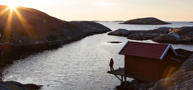A person standing on a dock next to a body of water.