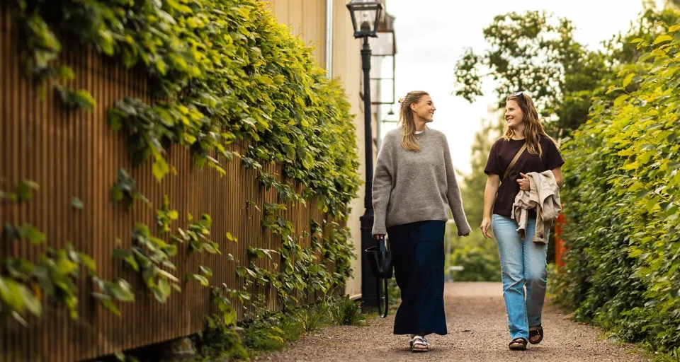 Ein paar Frauen, die eine unbefestigte Straße entlanggehen.