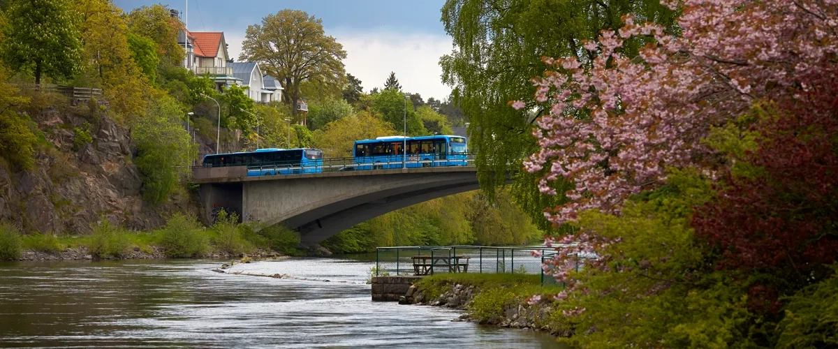 En blå buss som färdas över en bro över en flod.