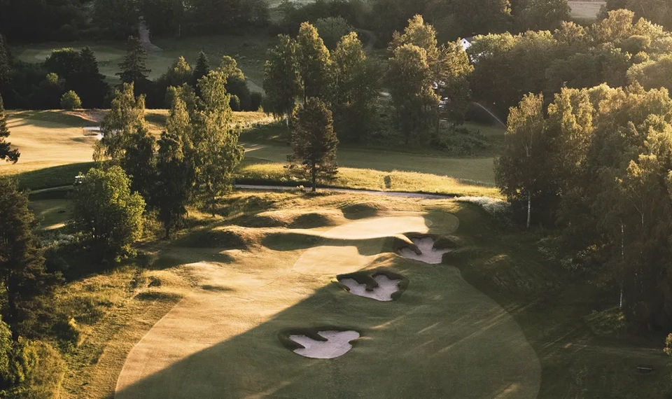 En flygbild av en golfbana omgiven av träd.