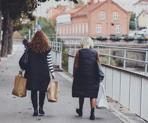 Två kvinnor promenerar med shoppingpåsar i händerna i centrala Strömstad