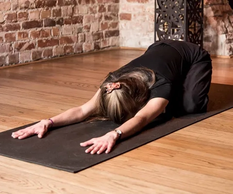 En kvinne gjør en yogastilling på en matte.