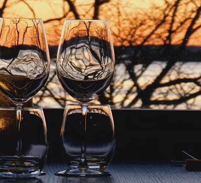 Två vinglas står på ett bord intill ett fönster.