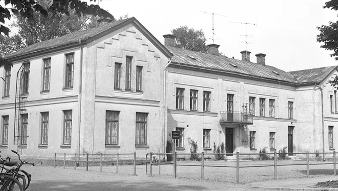 Ljus stor byggnad i vägkorsning, några cyklar i förgrunden