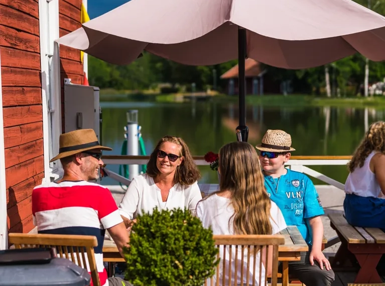 A group of people sitting at a table under an umbrella.