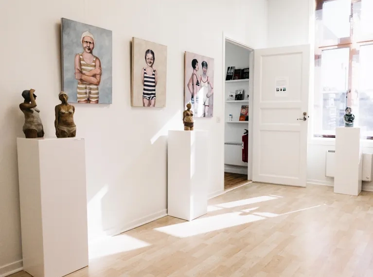 A white room with paintings and sculptures on the wall.