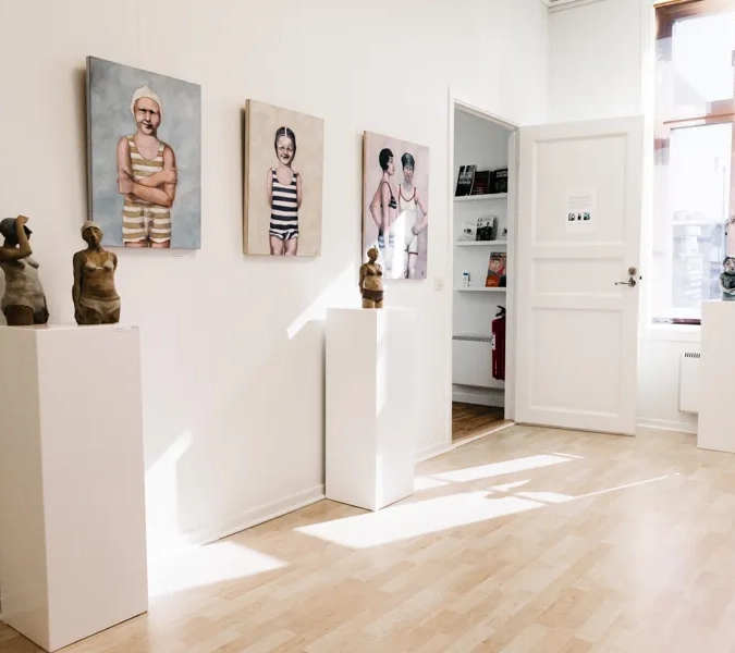 A white room with paintings and sculptures on the wall.