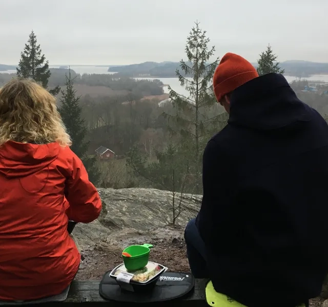 Två personer fikar på en utsiktsplats med utsikt över sjön Mjörn en lite grå men vacker vinterdag