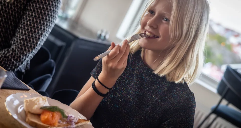 En liten flicka sitter vid ett bord och äter mat.