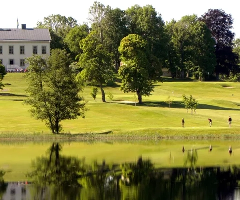 Ett stort vitt hus som ligger på ett grönskande fält.