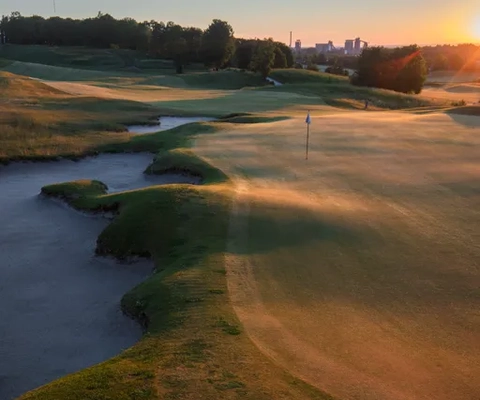 Solen går ner över en golfbana.