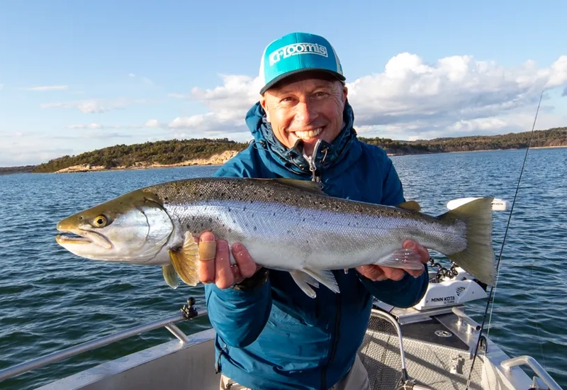 En man på en båt håller i en fisk.