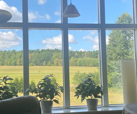 Ein mit Möbeln und einem großen Fenster ausgestattetes Wohnzimmer.