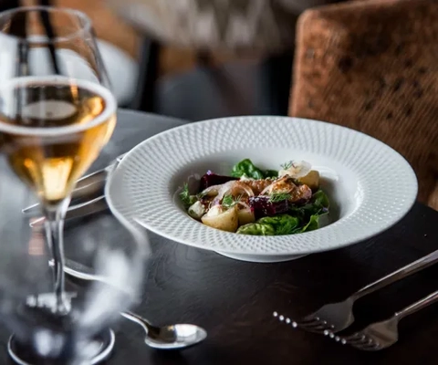 A plate of food and a glass of wine on a table.