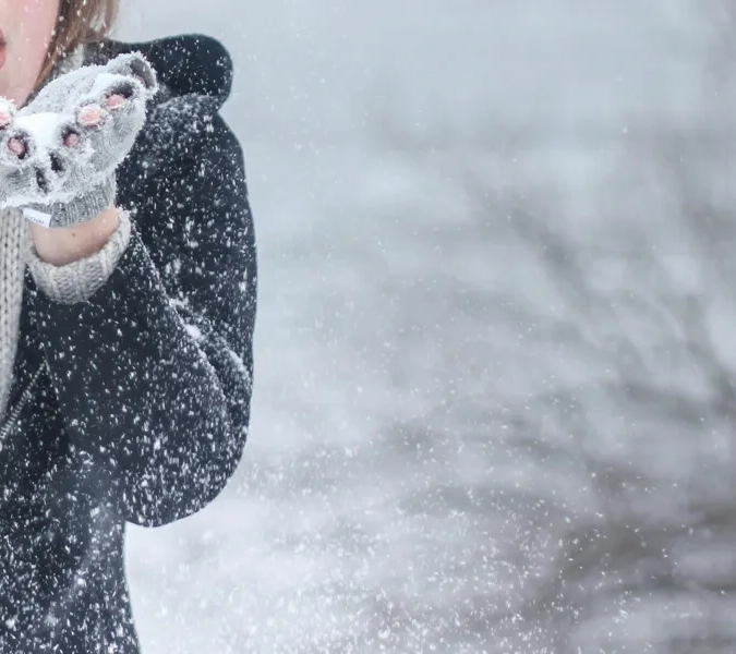 Person som blåser snö ur händerna