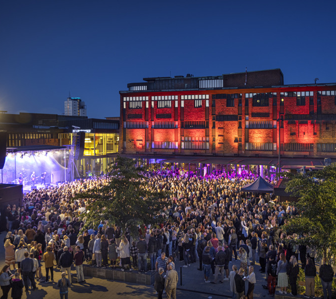 En folkmassa som står runt en byggnad på kvällen.